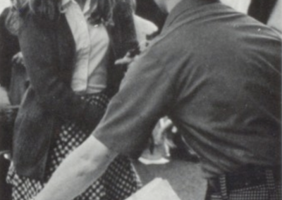 Ron Underwood speaking with two students at Beyer High School in the 1970s, smiling and engaging with them as they review materials together.